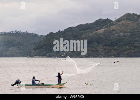 I pescatori usano un cast net presso il lago in Catemaco Catemaco, Veracruz, Messico. La tropicale lago di acqua dolce al centro della Sierra de Los Tuxtlas, è una destinazione turistica popolare e conosciuto per libera compresa scimmie, la foresta pluviale sfondo e streghe messicano noto come Brujos. Foto Stock