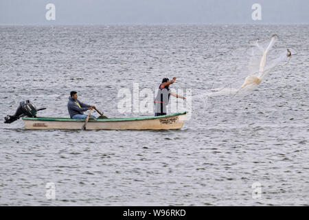 I pescatori usano un cast net presso il lago in Catemaco Catemaco, Veracruz, Messico. La tropicale lago di acqua dolce al centro della Sierra de Los Tuxtlas, è una destinazione turistica popolare e conosciuto per libera compresa scimmie, la foresta pluviale sfondo e streghe messicano noto come Brujos. Foto Stock