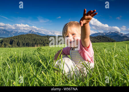 In Germania, in Baviera, Allgaeu, Happy Baby girl giocando nei campi Foto Stock