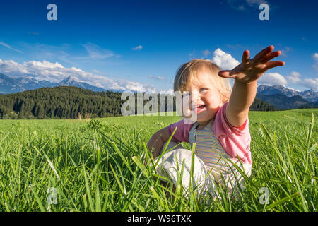 In Germania, in Baviera, Allgaeu, Happy Baby girl giocando nei campi Foto Stock