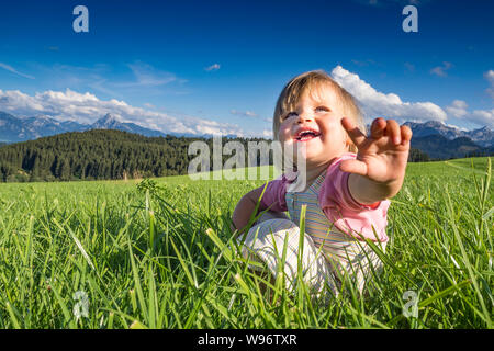 In Germania, in Baviera, Allgaeu, Happy Baby girl giocando nei campi Foto Stock