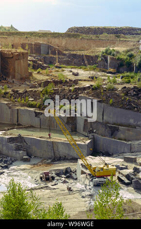 Pietra di granito strati miniera con gru di lavorare all'interno di rocce di caricamento Foto Stock