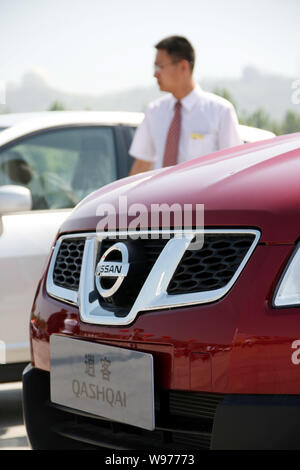 --FILE -- un venditore cinese sorge accanto alla Nissan Qashqai durante un auto show di Qingdao City East Chinas provincia di Shandong, 14 maggio 2011. Giapponese Foto Stock