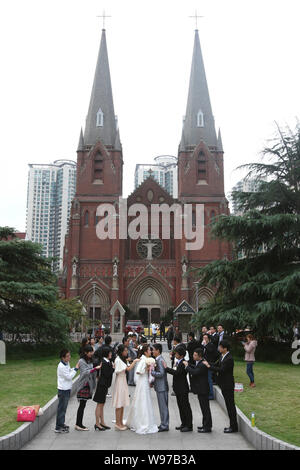 Una coppia di sposi in luna di miele cinese e il loro amico posare per foto di nozze di fronte al Sant Ignazio Cattedrale di Shanghai, noto anche come cateterismo Xujiahui Foto Stock