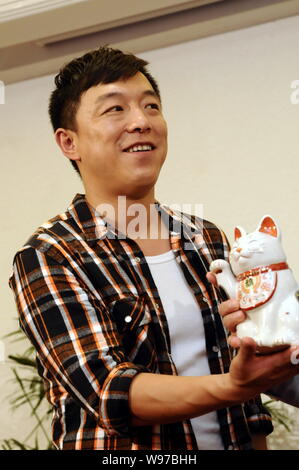 Attore cinese Huang Bo pone con porcellana Fortune Cat doll durante la conferenza stampa per il nuovo filmato, 101st proposta di matrimonio, in Cina a Shanghai, 7 Foto Stock