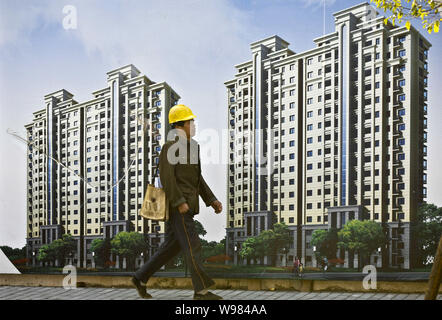 --FILE--un lavoratore cinese passeggiate passato un annuncio per un progetto residenziale in Cina a Shanghai, 22 dicembre 2010. Autorità di Chongqing e sh Foto Stock