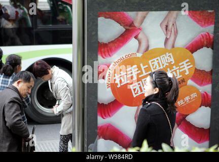 --FILE--Cinesi locali residenti stare accanto a un annuncio online per il gruppo di acquisto lashou.com sito in corrispondenza di una stazione di autobus in Cina a Shanghai, 18 Marzo 2 Foto Stock