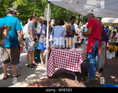 Mercato degli Agricoltori, Madison, WI, Stati Uniti d'America. Aug 2018. Giovane uomo acquistando alcuni dadi da questo fornitore. Foto Stock