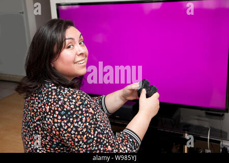 Di fronte a una schermata vuota con copia spazio, una persona che sta guardando sopra la spalla sorridendo pur avendo un buon momento per giocare con i videogiochi Foto Stock