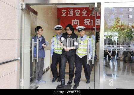 Musicista cinese e porcellane Got Talent giudice Gao Xiaosong, seconda a destra, passeggiate fuori da una stazione di polizia con due poliziotti dai suoi lati in Pechino, C Foto Stock