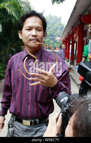 Un uomo cinese soprannominato Feng mostra fuori le sue unghie lunghe nel centro della città di Haikou, sud Chinas Hainan Provincia, 13 marzo 2011. Foto Stock