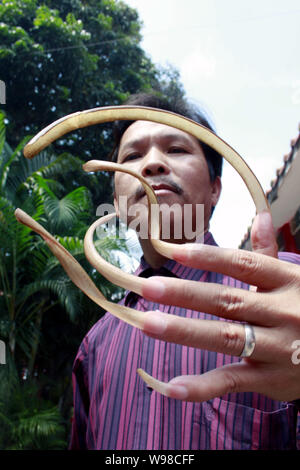 Un uomo cinese soprannominato Feng mostra fuori le sue unghie lunghe nel centro della città di Haikou, sud Chinas Hainan Provincia, 13 marzo 2011. Feng ha detto ai giornalisti che egli Foto Stock