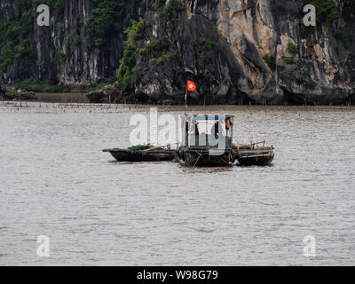 Tradizionale vietnamita barche da pesca in acqua nella baia di Ha Long, nel Vietnam del nord, battenti bandiera vietnamita Foto Stock