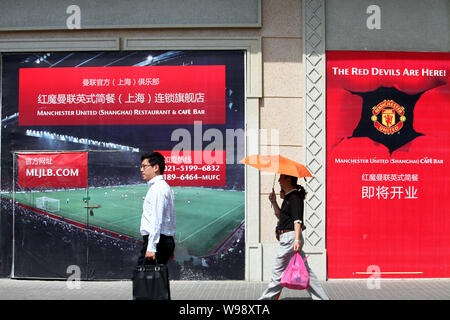 --FILE--Cinesi locali residenti a piedi passato a presto da aprire il Manchester United Ristorante e bar caffetteria in Cina a Shanghai, 18 maggio 2011. L'Americano Foto Stock