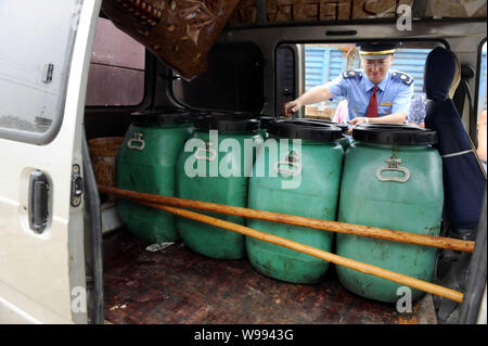 --FILE -- una legge cinese enforcement officer mette di barili di olio di scarto in un furgone a un sistema illegale di officina in cui l'olio da cucina è costituito da olio di scarto dragati f Foto Stock