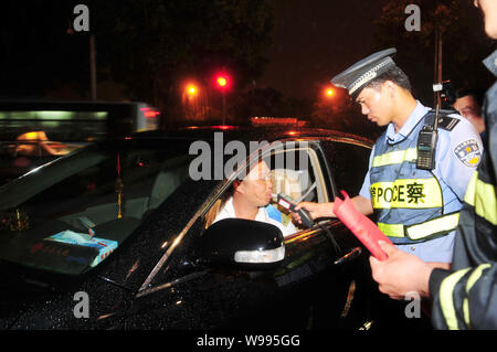 Un Cinese funzionario di polizia usa un rivelatore per misurare il livello di alcol nel sangue di un operatore durante la guida in stato di ebbrezza la prova in città di Fuzhou, sudest C Foto Stock