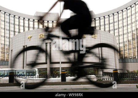 --FILE--un ciclista cavalca la sua moto passato la sede e sede dei popoli Banca di Cina (PBOC), porcellane banca centrale di Pechino, Cina, 10 Foto Stock