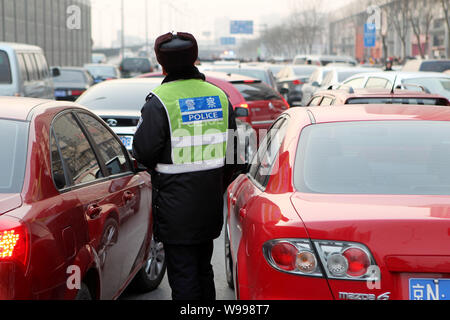 --FILE--un cinese police officer dirige il traffico in mezzo ad una folla di automobili su una strada a Pechino, in Cina, il 3 gennaio 2011. Pechino il venerdì (1 aprile 2011) Foto Stock