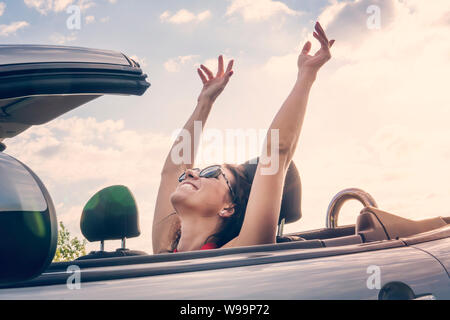 Felice ragazza rilassante godendo il sole seduti in auto convertibili in estate viaggio vacanza la guida di distanza sul viaggio. Concetto di libertà sentimento donna Foto Stock