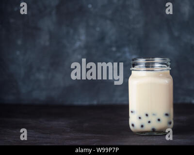 Tè delle bolle di latte fatto in casa con palle di Tapioca Pearls. Popolare tisana bolla in vaso di vetro mason con spazio di copia per il testo. Il tè bolle su sfondo scuro. Foto Stock