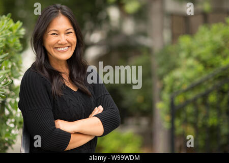 Ritratto di una donna asiatica seduta fuori. Foto Stock