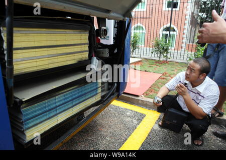 Visitatori cinesi guardare le batterie di un bus elettrico durante la cerimonia di lancio di una stazione di carica di membro Grid Corporation della Cina in Xiame Foto Stock