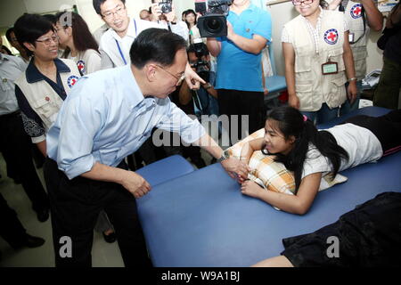 Hong Kong SAR (regione amministrativa speciale) Chief Executive Donald Tsang Yam-kuen, anteriore sinistra, saluta una ragazza cinese che ha perso la gamba in maggio 12 Foto Stock