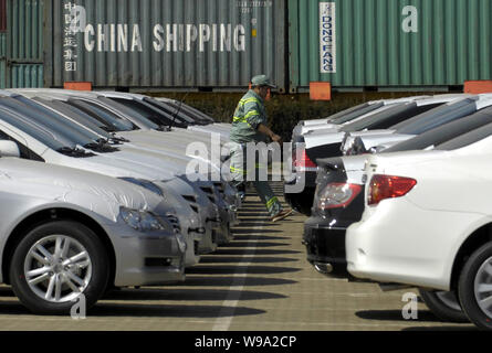 --FILE--un lavoratore cinese passeggiate ultimi ranghi di auto per essere spediti al Porto di Tianjin, Cina, 1 aprile 2009. Il governo cinese è accelerare th Foto Stock