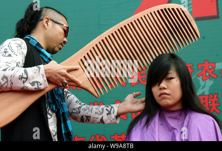 Un Cinese parrucchiere utilizza un pettine gigante su una giovane donna cinese per lo styling dei capelli nella città di Changsha, porcellane centrale nella provincia del Hunan, 1 dicembre 2010. Foto Stock