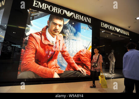 --FILE--una donna cinese passeggiate passato un pulitore di fronte un Emporio Armani boutique in un centro commerciale per lo shopping nella città di Shenyang, nordest Chinas Liaoning pro Foto Stock