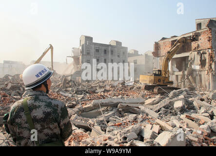 --FILE -- una legge cinese enforcement officer orologi le demolizioni forzate di presunte illegalmente-costruito case nella città di Wuhan, central Chinas Hubei provin Foto Stock