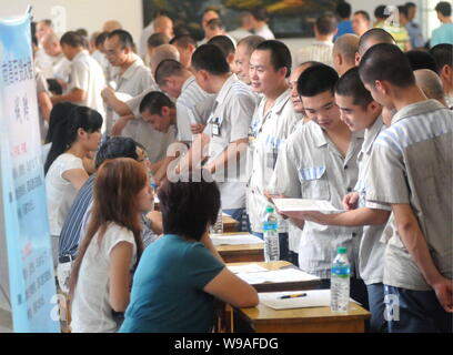 Maschio cinese detenuti che completeranno il loro periodo di reclusione folla alcune cabine di compaines durante una fiera del lavoro in un carcere di Nanchang, Oriente Cina Foto Stock