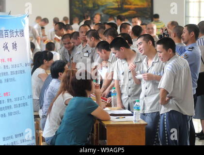 Maschio cinese detenuti che completeranno il loro periodo di reclusione folla alcune cabine di compaines durante una fiera del lavoro in un carcere di Nanchang, Oriente Cina Foto Stock