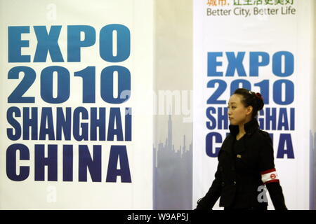 Un metro cinese lavoratore passeggiate passato manifesti pubblicitari per il World Expo 2010 a una stazione della metropolitana di Shanghai, Cina, 19 aprile 2010. Shanghai è pou Foto Stock