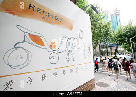 Locali residenti cinesi a piedi passato un annuncio per Hermes al di fuori della Hermes Mansion di Luwan District in Cina a Shanghai, 9 agosto 2010. Francese Foto Stock