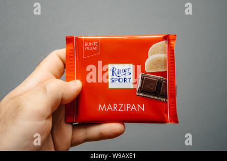 Parigi, Francia - Apr 27, 2019: Man mano che tiene la deliziosa Ritter Sport con cioccolato al sapore di marzapane contro uno sfondo grigio Foto Stock