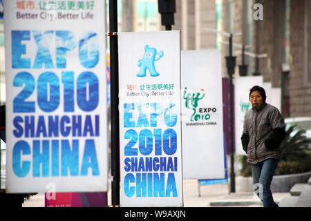 --FILE--una donna cinese passeggiate passato manifesti pubblicitari per il World Expo 2010 a Shanghai, in Cina, il 28 dicembre 2009. La canzone di promozione per gli Shan Foto Stock