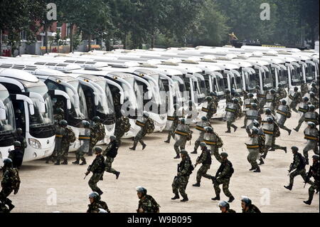 Cinese poliziotti paramilitari rush per gli autobus durante una distribuzione trapano a Pechino in Cina, 2 settembre 2010. La polizia di Pechino autorità detenevano 8 dr Foto Stock