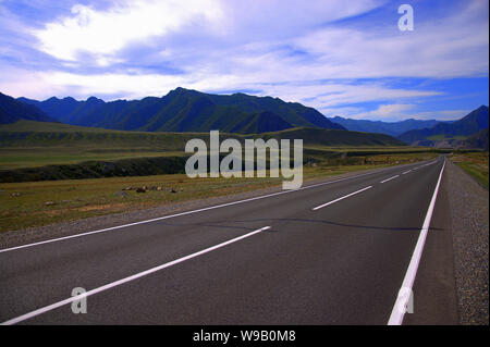 Paesaggio di strada lastricata, strada diritta va al di là dell'orizzonte attraverso le montagne. Kurai steppa, Altai, Russia. Foto Stock