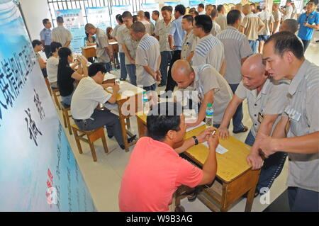 Maschio cinese detenuti che completeranno il loro periodo di reclusione folla alcune cabine di compaines durante una fiera del lavoro in un carcere di Nanchang, Oriente Cina Foto Stock