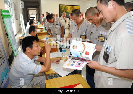 Maschio cinese detenuti che completeranno il loro periodo di reclusione folla alcune cabine di compaines durante una fiera del lavoro in un carcere di Nanchang, Oriente Cina Foto Stock