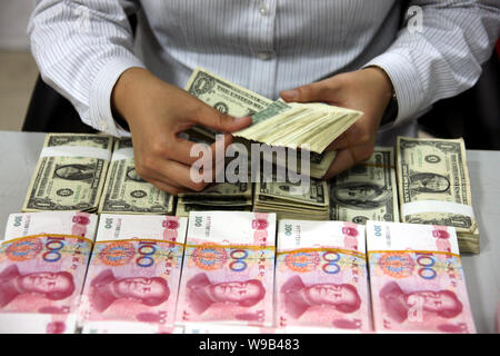 Un addetto cinese conta banconote americane accanto a RMB (renminbi yuan) banconote presso una banca in città Huaibei, est Chinas provincia di Anhui, 12 novembre 2 Foto Stock