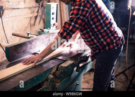 Bel giovane falegname la lavorazione del legno nel suo laboratorio di falegnameria, falegname titolare di azienda Foto Stock