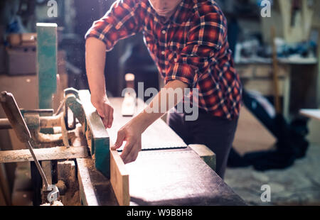 Bel giovane falegname la lavorazione del legno nel suo laboratorio di falegnameria, falegname titolare di azienda Foto Stock