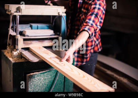 Bel giovane falegname la lavorazione del legno nel suo laboratorio di falegnameria, falegname titolare di azienda Foto Stock