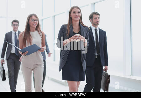 La gente di affari andando lungo il corridoio di ufficio durante la giornata di lavoro Foto Stock