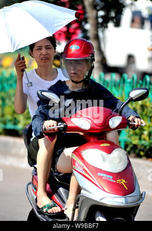 I ciclisti cinesi un giro in scooter sotto il sole cocente sulla strada nel clima soffocante in Yiwu City East Chinas nella provincia di Zhejiang, 3 Au Foto Stock