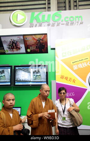 I monaci cinesi stare accanto a una donna allo stand di Ku6.com durante l'ottava China Digital Entertainment Expo e conferenza, noto come ChinaJoy 2010, in Foto Stock