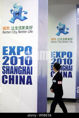 Un metro cinese lavoratore passeggiate passato manifesti pubblicitari per il World Expo 2010 a una stazione della metropolitana di Shanghai, Cina, 19 aprile 2010. Shanghai è pou Foto Stock