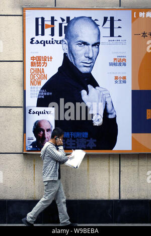 Un uomo cinese passeggiate passato un poster pubblicitario per la Cinese-versione 2010 numero di novembre di Esquire con l immagine del francese ex superstar soccer Foto Stock